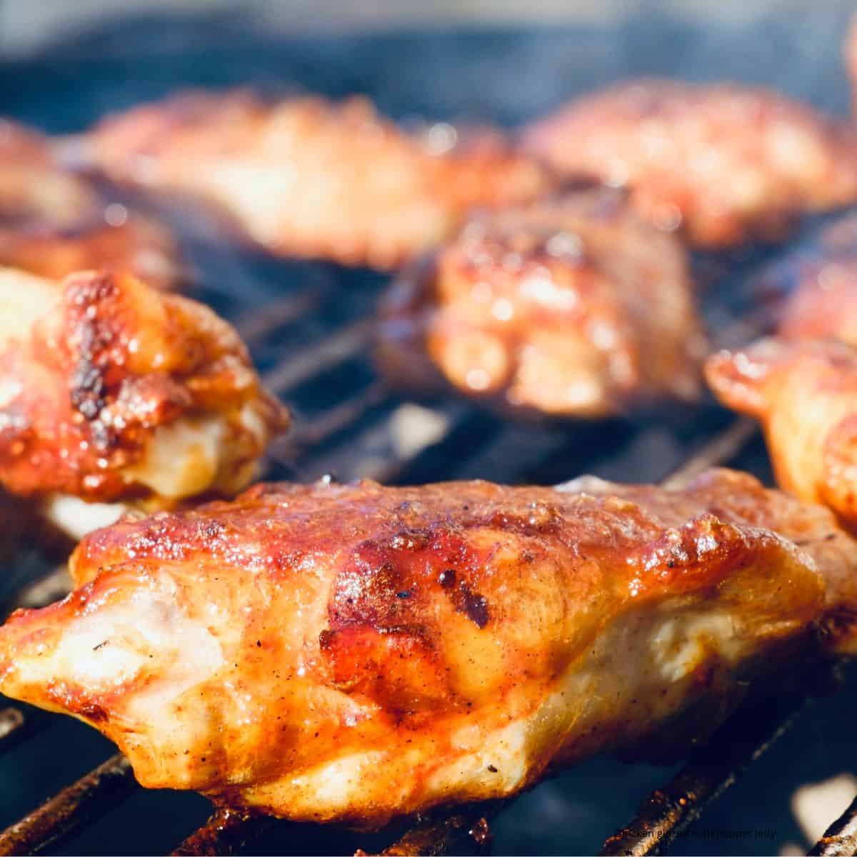 Chicken on the grill that has been glazed with pepper jelly.